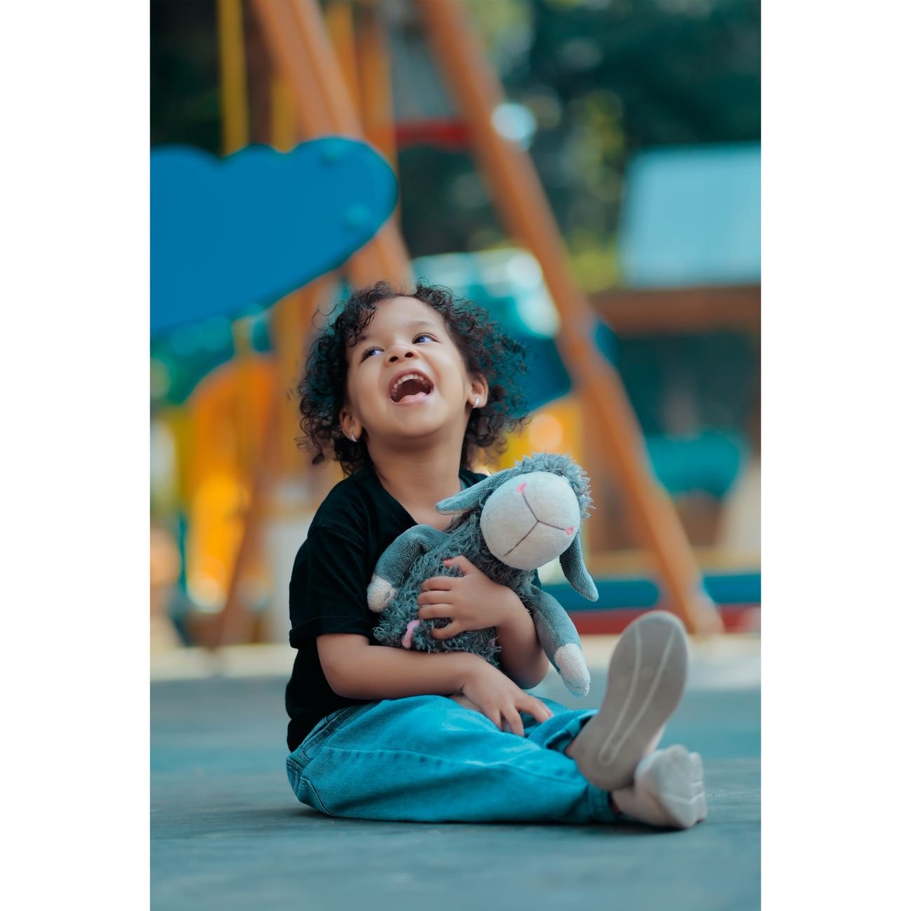Joyful child laughing while hugging a plushie at a playground